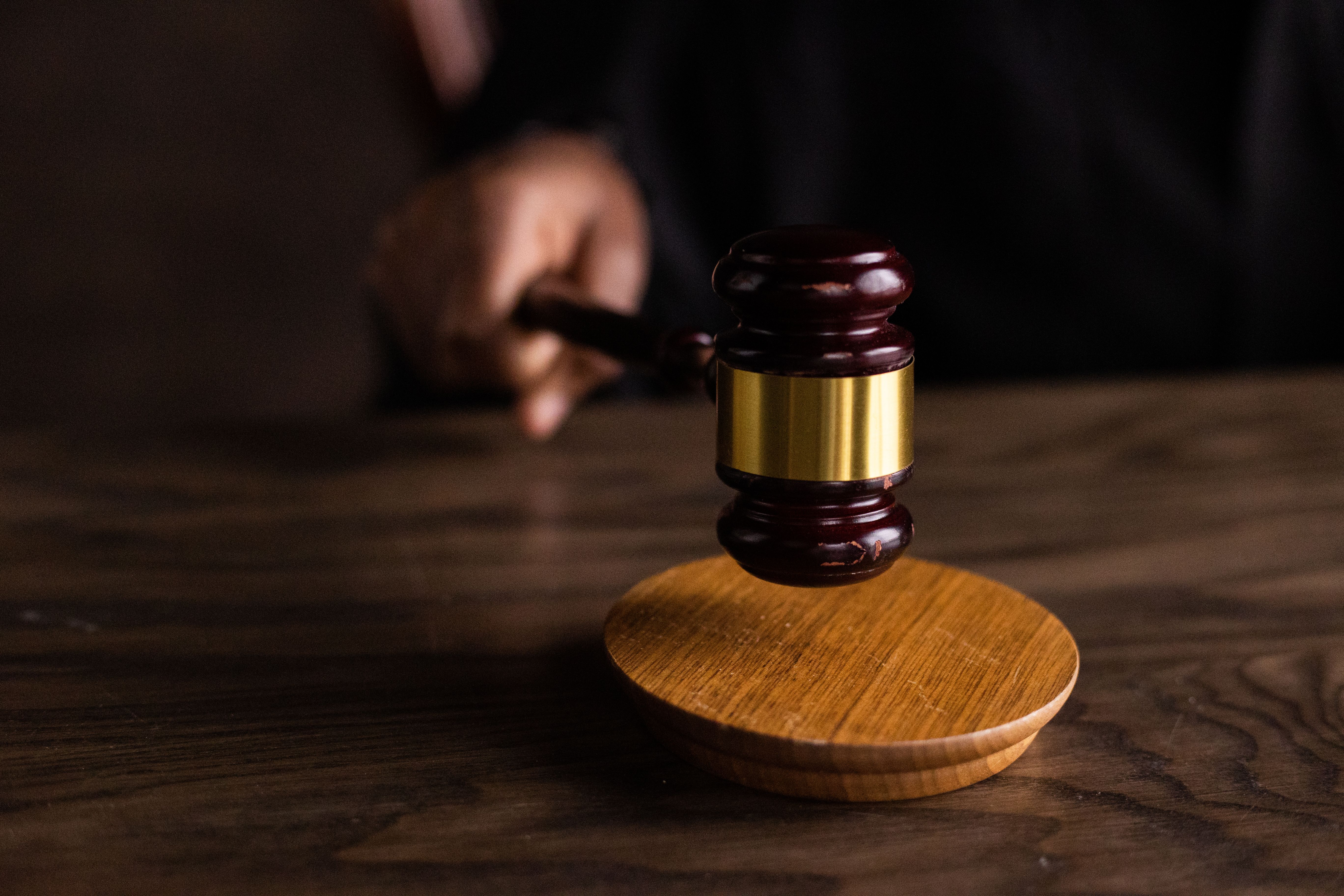 A gavel striking a sound block, symbolizing justice and legal authority in a courtroom setting